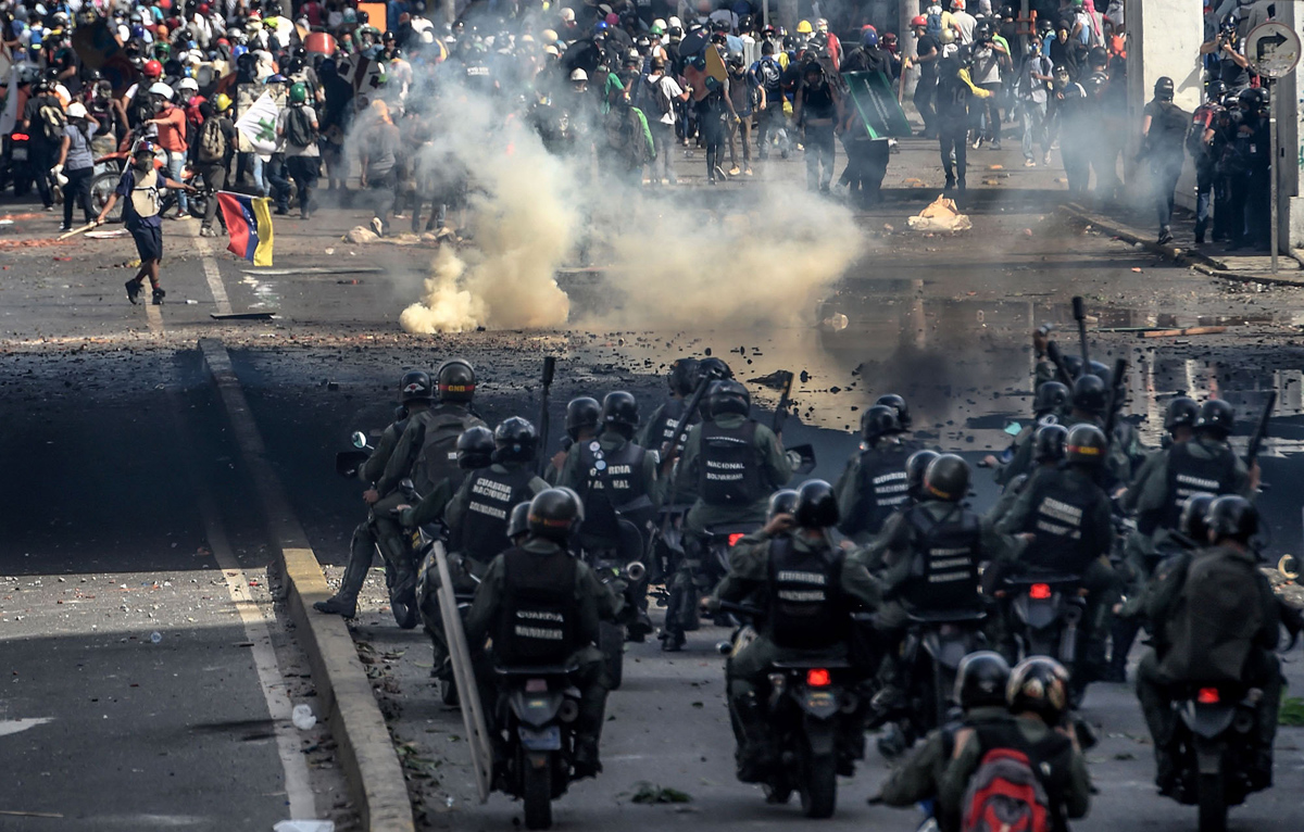 TOPSHOT - Riot police officers confront opposition activists during a demonstration against Venezuelan President Nicolas Maduro in Caracas, on May 26, 2017. 
Riot police in Venezuela fired tear gas and water cannon to stop anti-government protesters from marching on a key military installation Friday during the latest violence in nearly two months of unrest. / AFP PHOTO / Juan BARRETO        (Photo credit should read JUAN BARRETO/AFP/Getty Images)