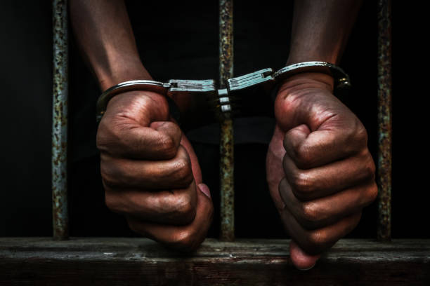 Prisoner holding metal cage in jail, no freedom concept
