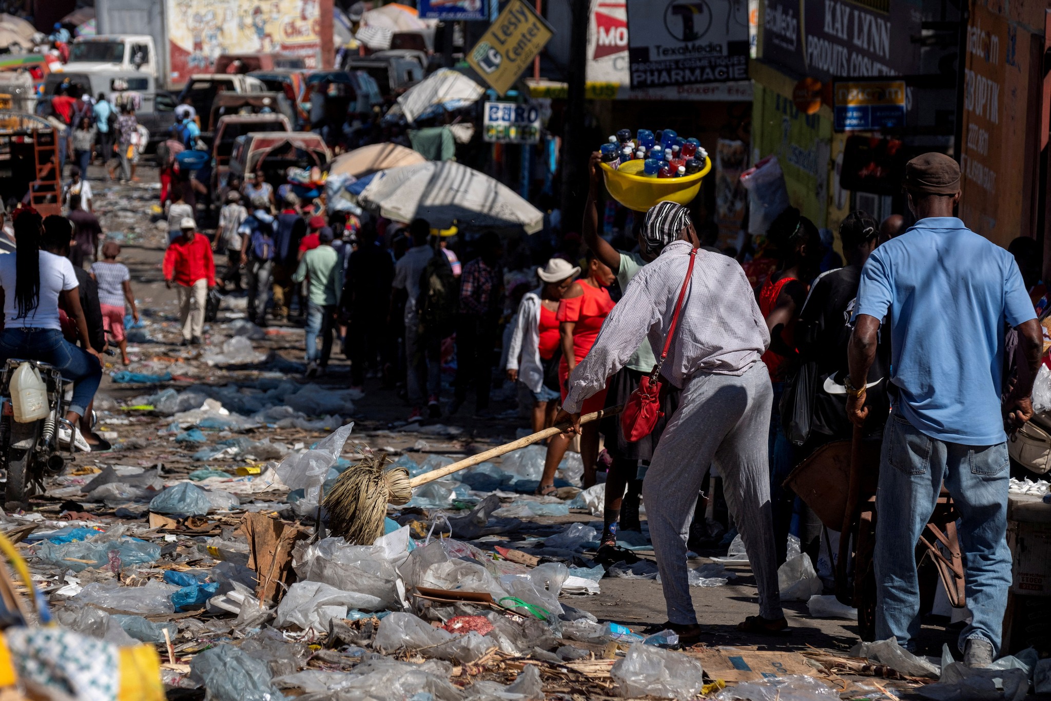 FILE PHOTO: A woman sweeps trash from the sidewalk to the street days after Haiti police blocked streets and broke into the airport during a protest demanding justice for fellow police officers killed by armed gangs, in Port-au-Prince, Haiti February 1,2023. REUTERS/Ricardo Arduengo/File Photo
