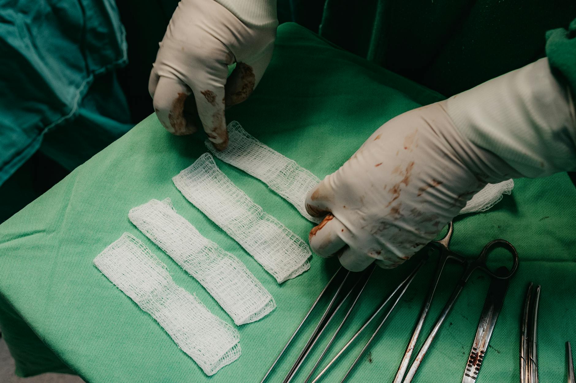 hands in gloves holding bandages